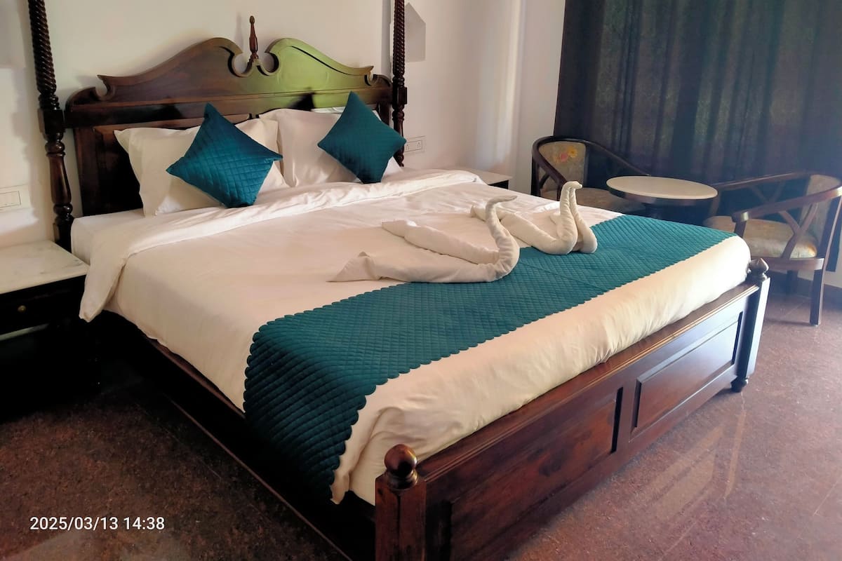 A neatly made bed with a wooden headboard, white and teal bedding, and a decorative towel arrangement.