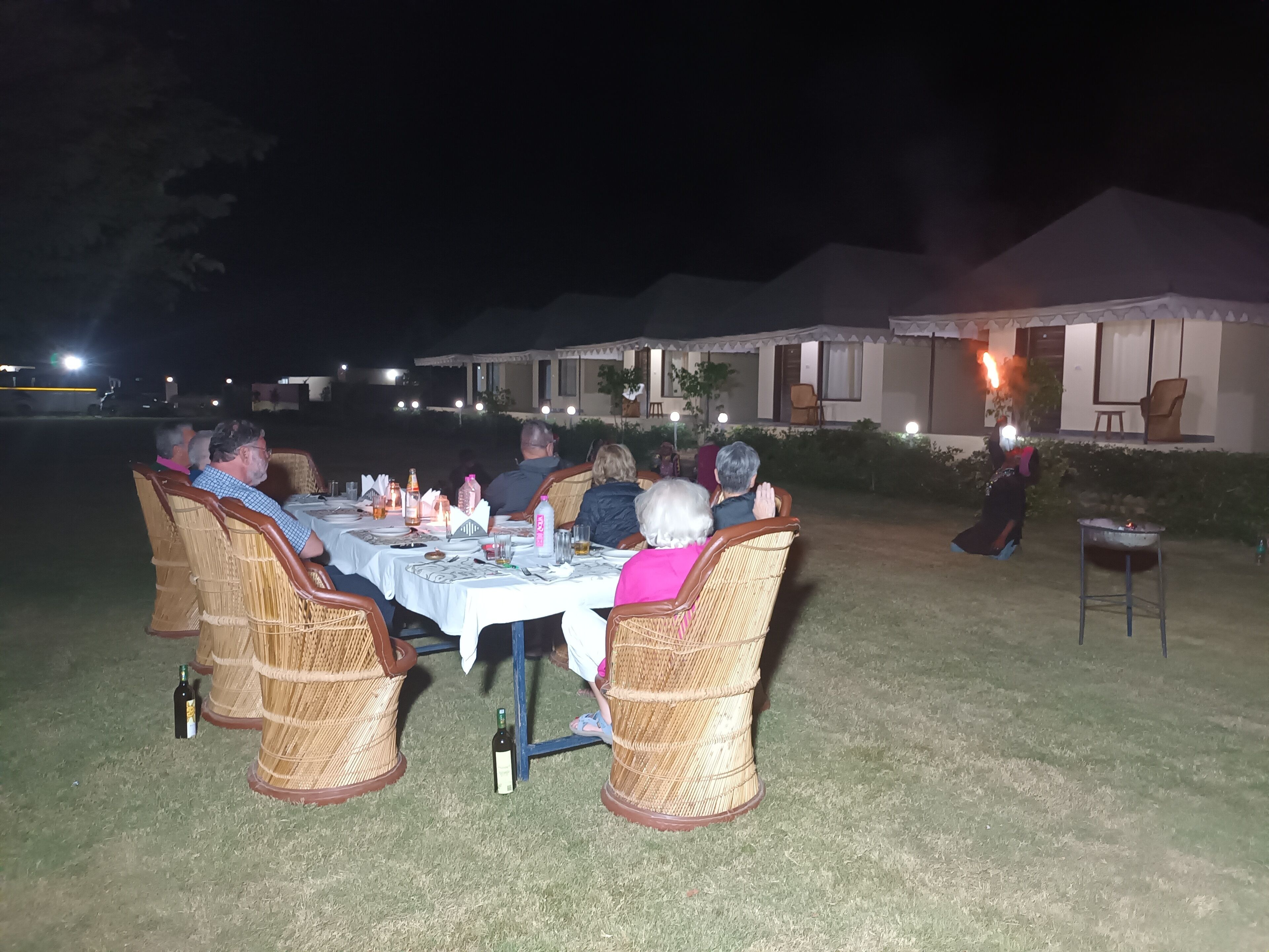 An outdoor dining area with wicker chairs and a table set for a meal.