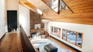 Ein Holzinnenraum mit Kamin, einer Chandelier und großen Fenstern.