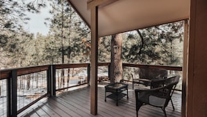 Eine Holzterrasse mit Korbmöbeln und Blick auf einen Wald.