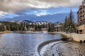 A view of a river with a waterfall, surrounded by trees and buildings. - Downtown Breck Ski In Ski Out! Walk to Everything (Breckenridge)