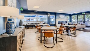 A modern indoor dining area with tables and chairs, a fireplace, and large windows offering a view outside. - Downtown Breck Ski In Ski Out! Walk to Everything (Breckenridge)