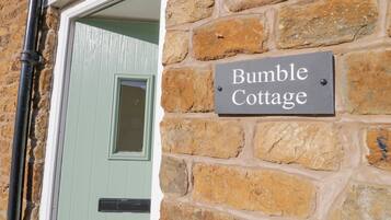 Un muro de piedra con un letrero que dice "Bumble Cottage".