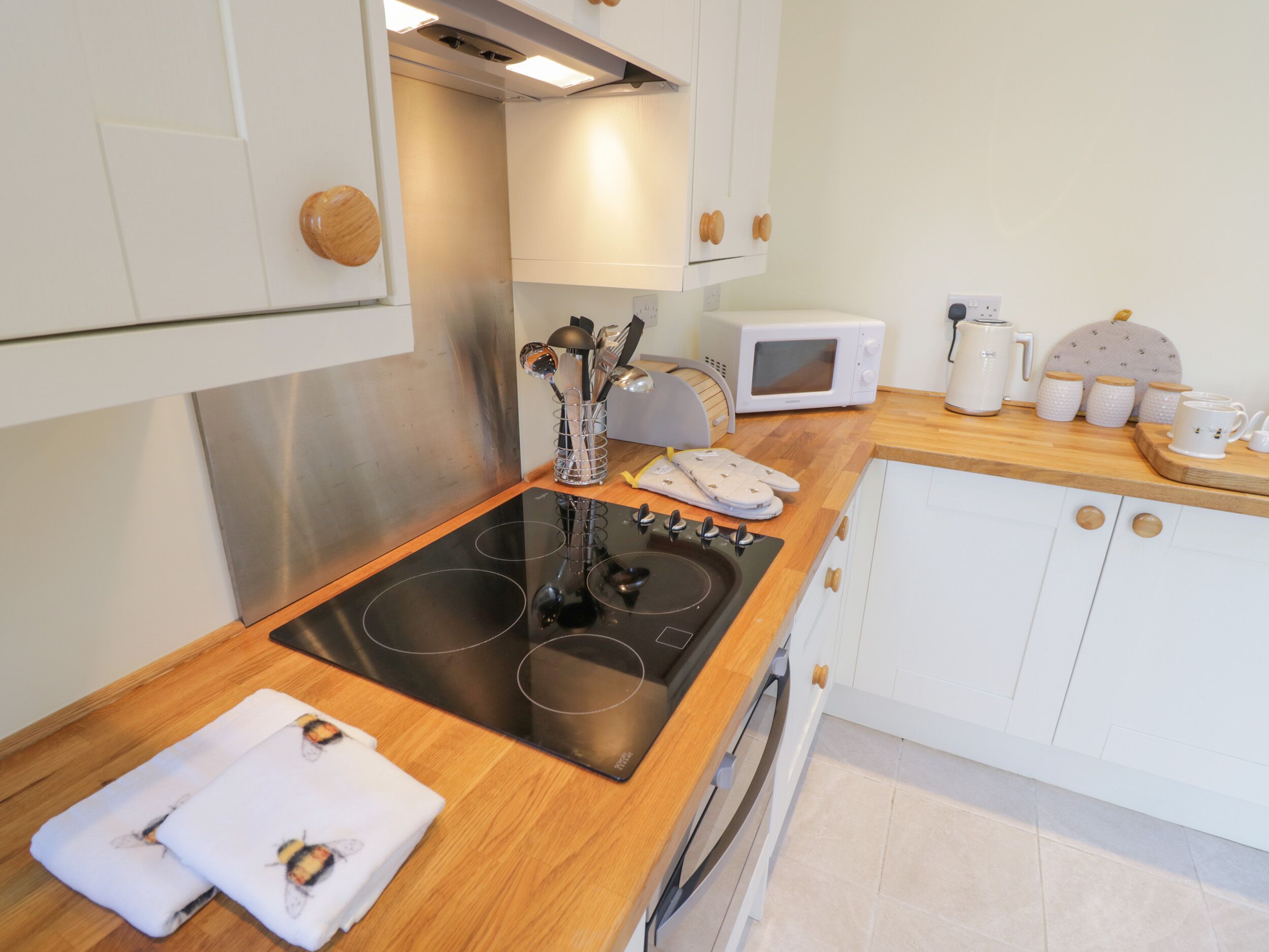 A modern kitchen with a black induction cooktop, white cabinets, and a microwave.