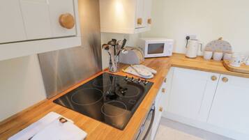 A modern kitchen with a black induction cooktop, white cabinets, and a microwave.