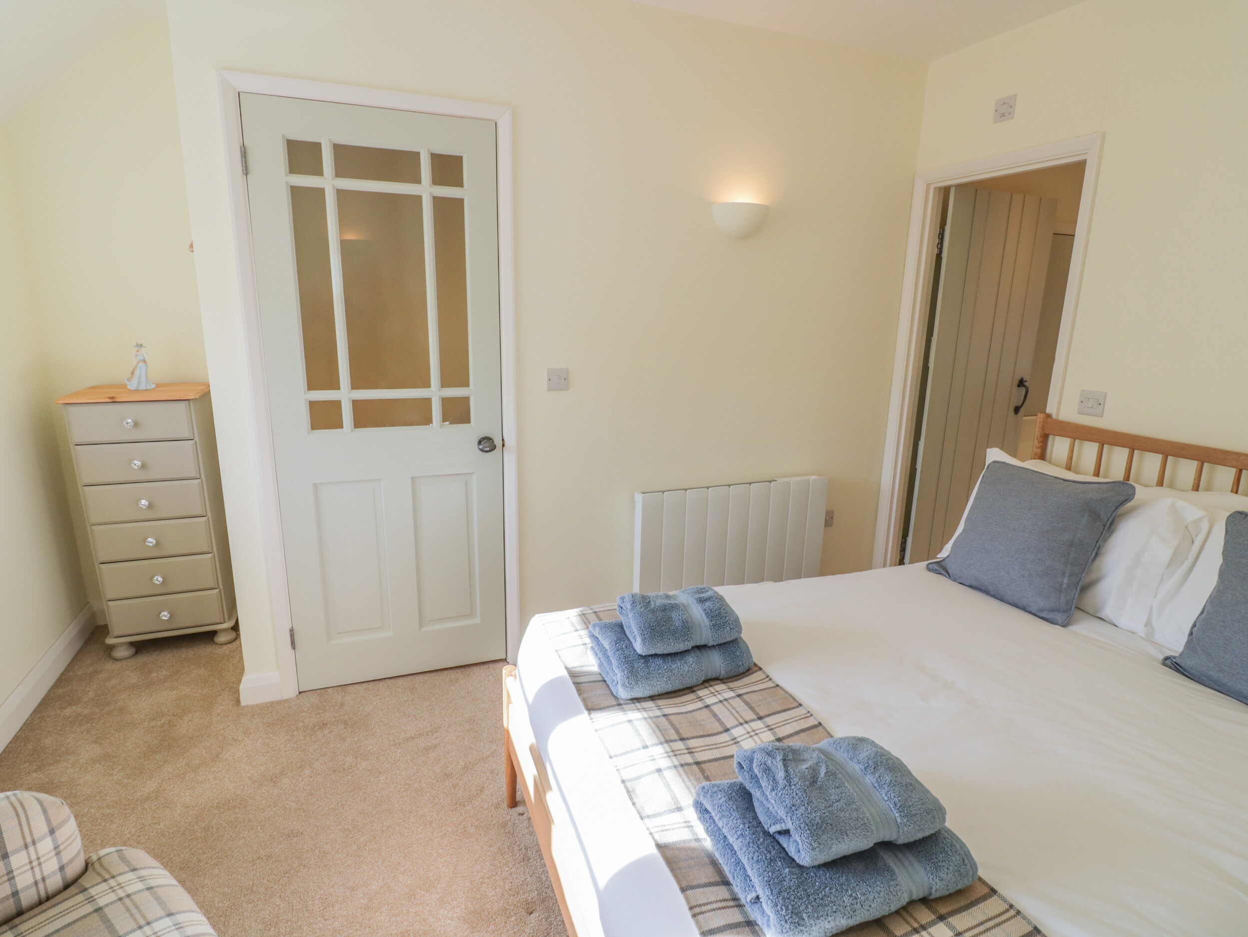 A bedroom with a bed, a dresser, a radiator, and a door.