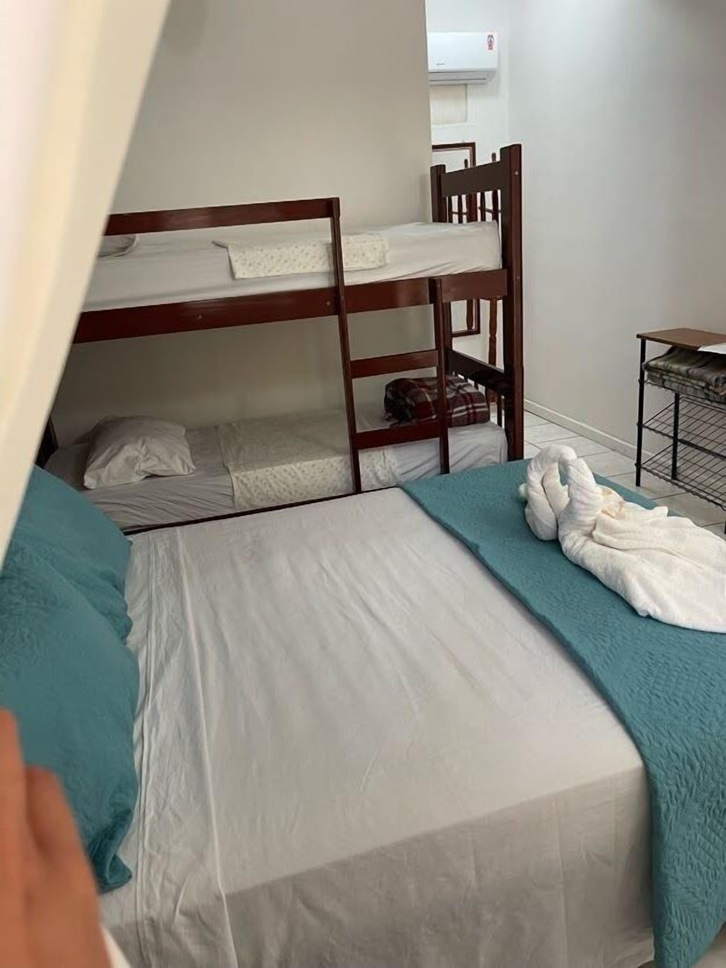 Un dormitorio con literas, una cama individual y una pequeña mesa con una silla.