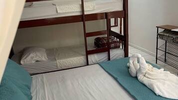 Un dormitorio con literas, una cama individual y una pequeña mesa con una silla.