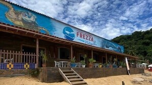 A beachside restaurant named 'FREZZA' with a mural of a sea creature on the facade.