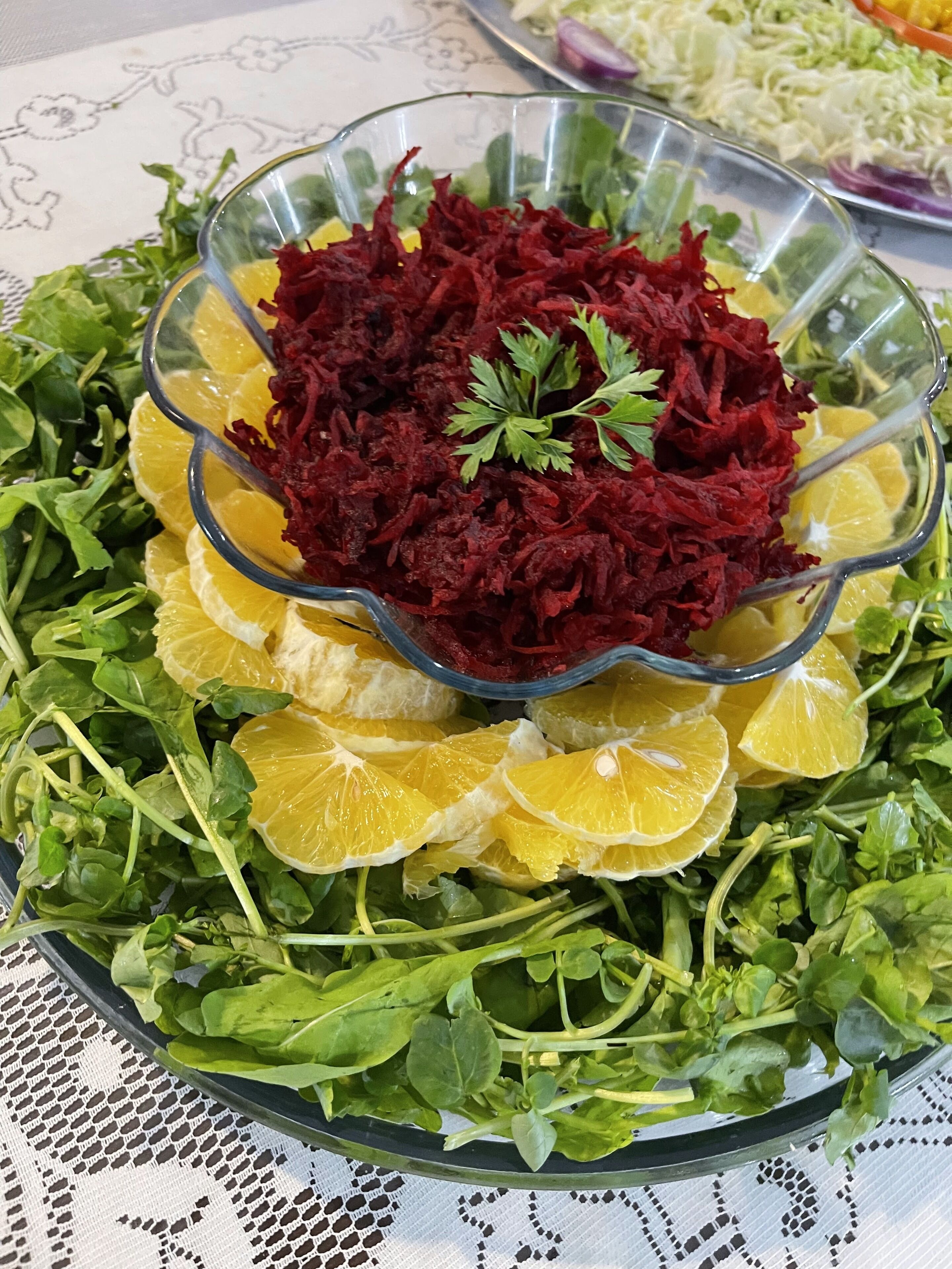 A salad bowl with beetroot and orange slices on a tablecloth.