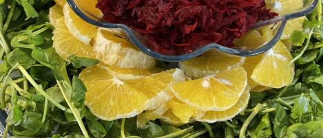 A salad bowl with beetroot and orange slices on a tablecloth.