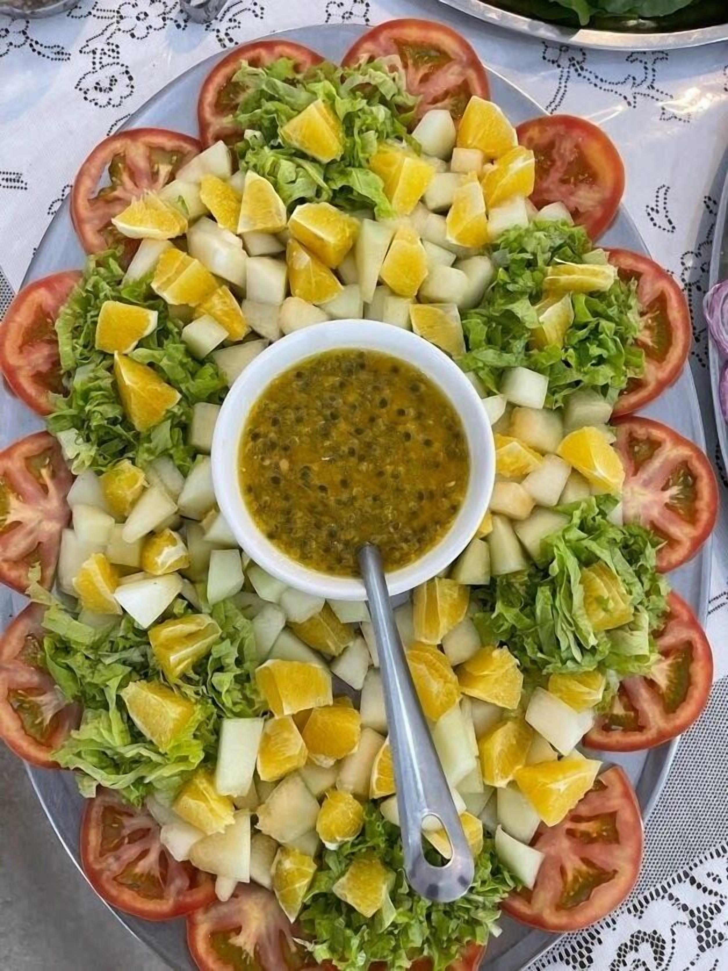 Ensalada amb tomàquets, lletuga i trossos de llimona, tot envoltat d'un bol de salsa.