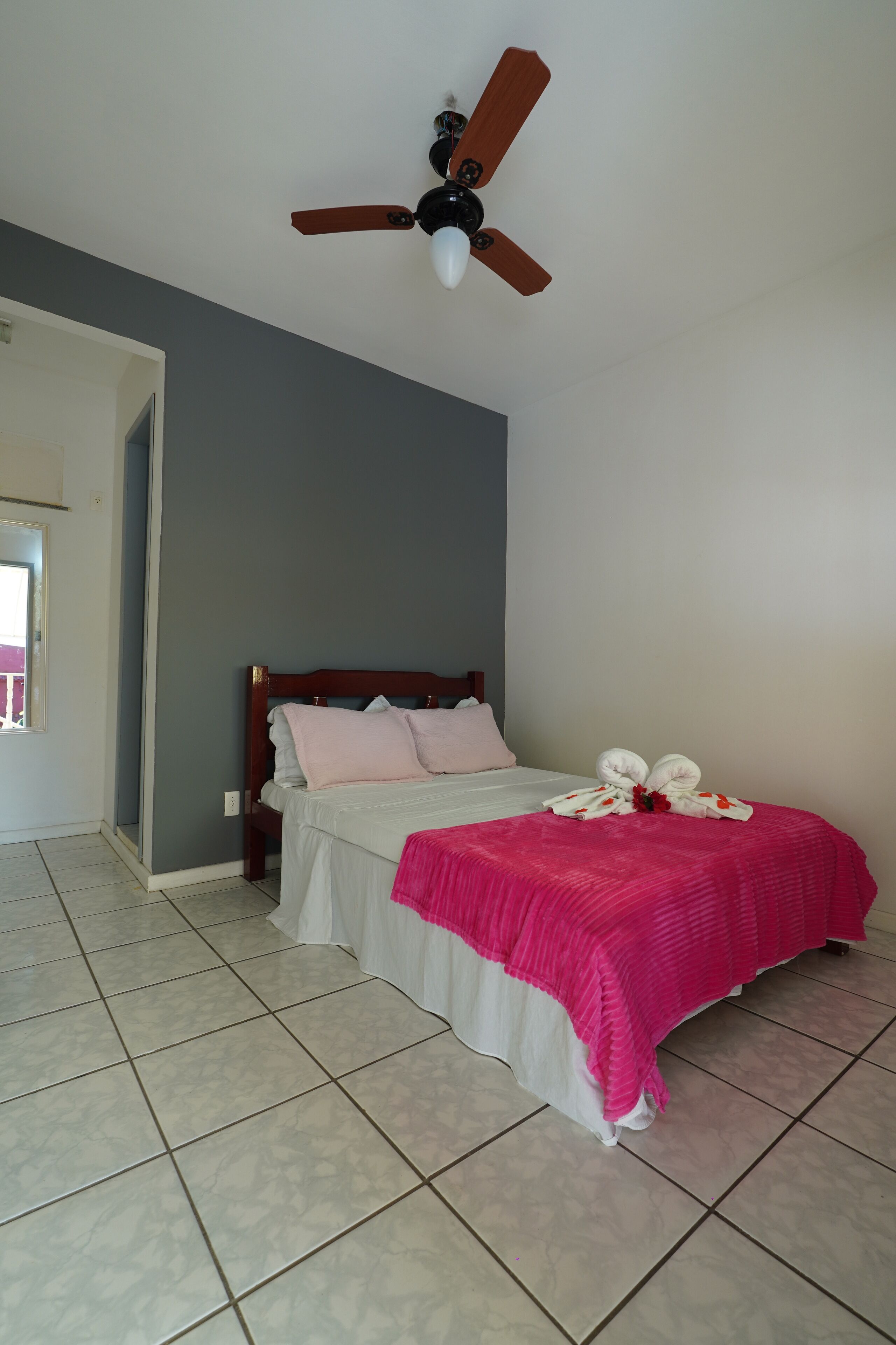 A bedroom with a bed, a ceiling fan, and a window.