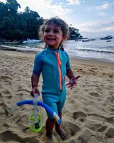 Un niño en una playa arenosa sosteniendo un snorkel y una máscara.