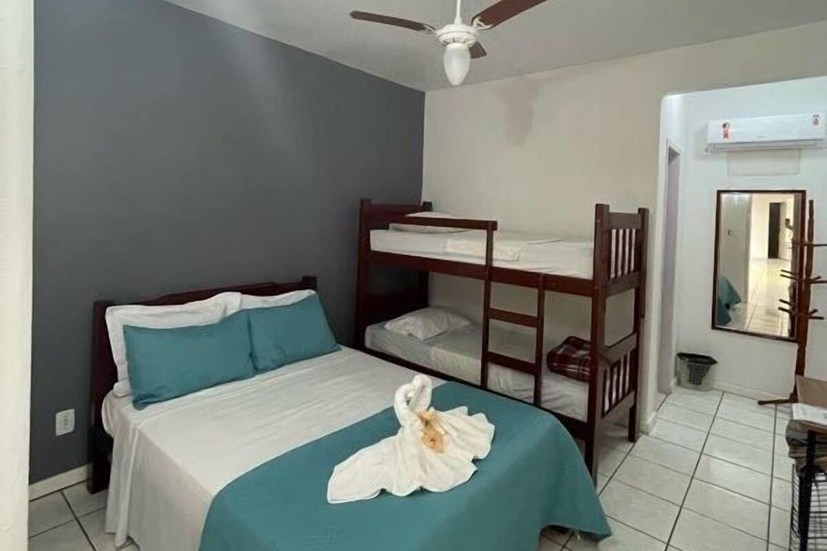 A bedroom with a single bed, a bunk bed, a ceiling fan, and a mirror.