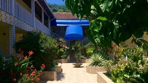 A courtyard with a tiled pathway leading to a building with a blue awning.