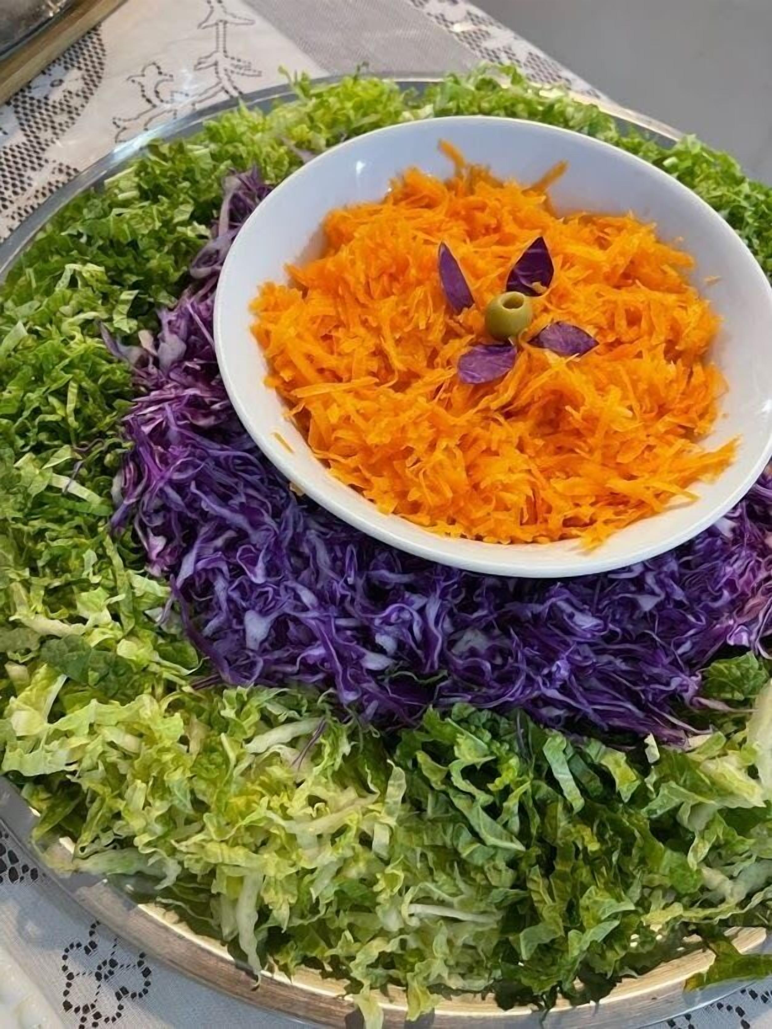 A salad with shredded carrots and purple cabbage on a plate.