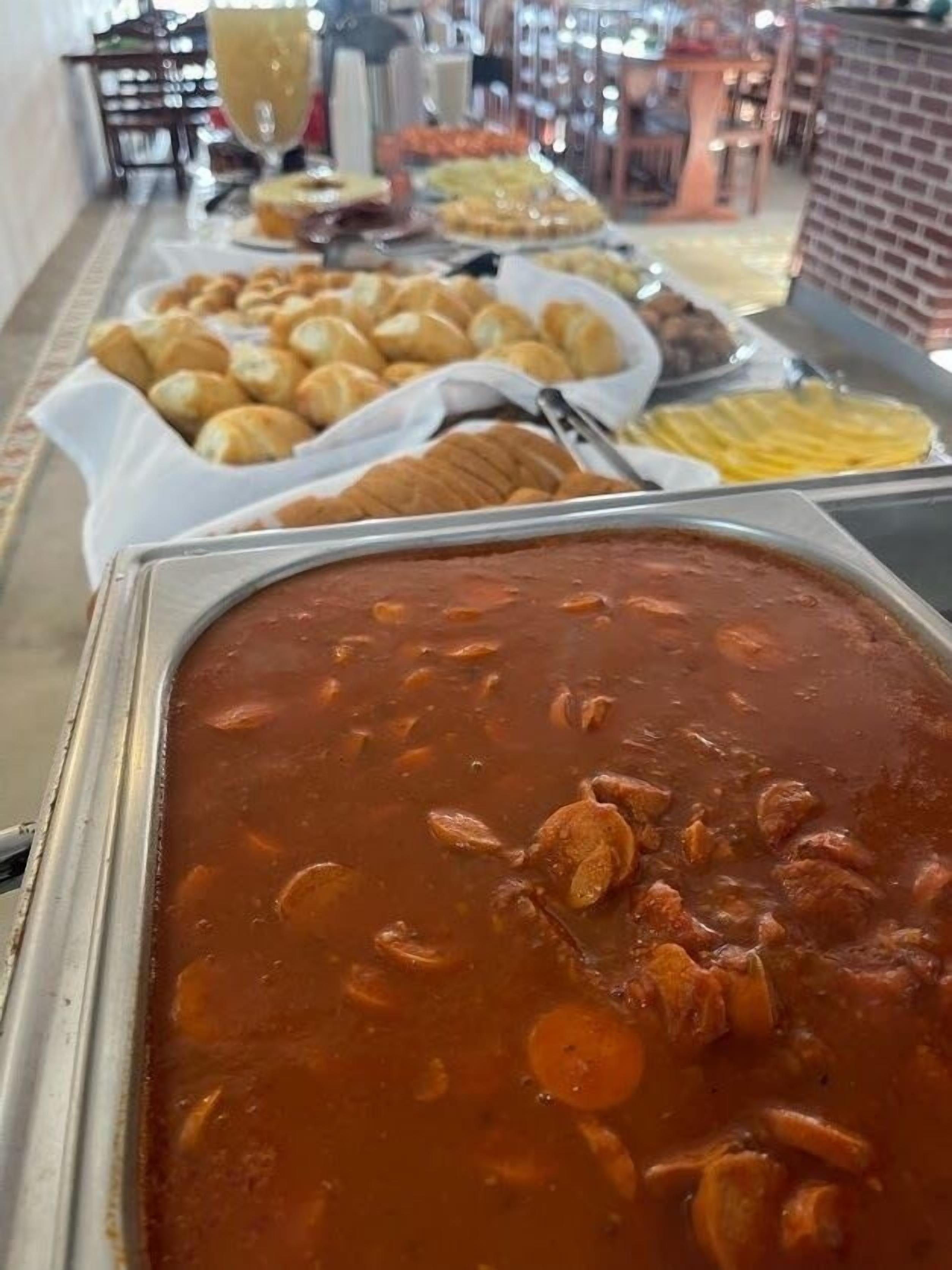A buffet with various dishes including a large pot of stew and several trays of pastries.