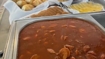 Een buffet met diverse gerechten, waaronder een grote pan stoofpot en verschillende schalen gebak.