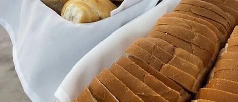 A variety of baked goods displayed on a table, including bread rolls and sliced bread.