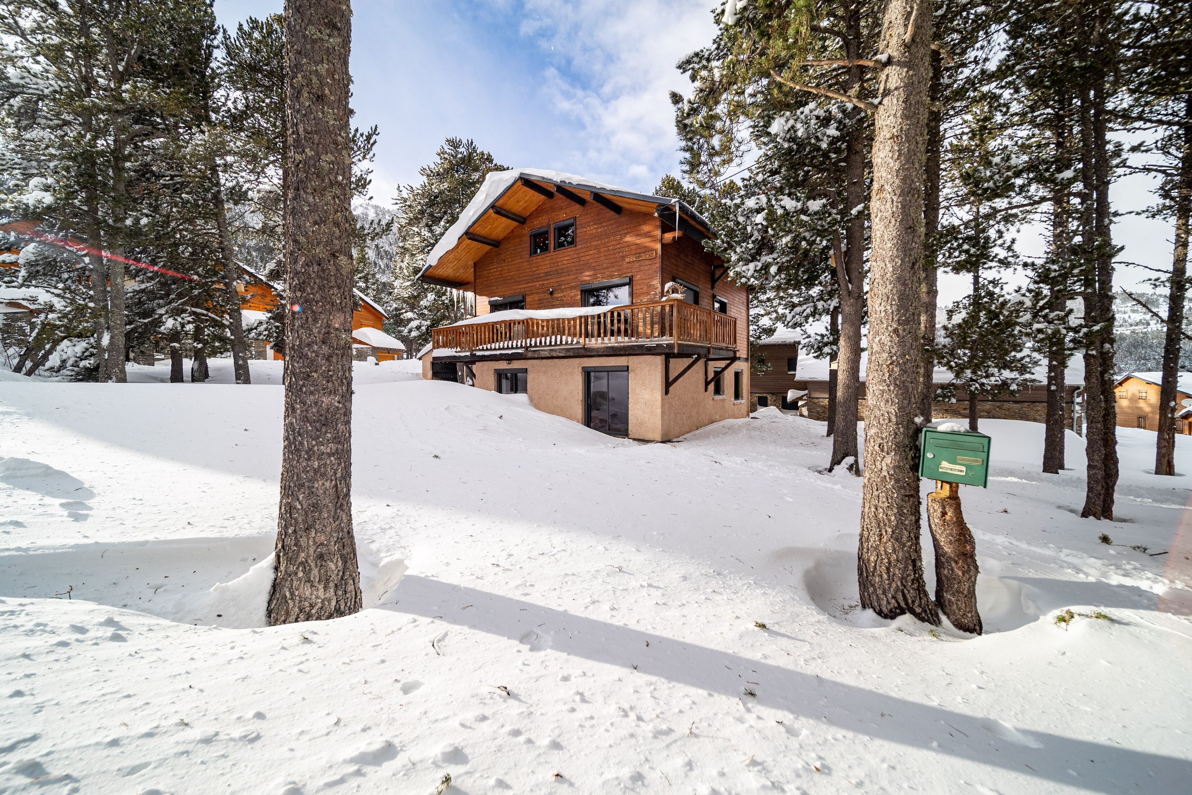 A wooden cabin with a balcony, surrounded by snow-covered trees.