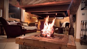 A cozy living room with a fireplace, wooden furniture, and a stone fireplace surround. - Chalet Vinson Luxury 5-Les Gets- 12 pers -jacuzzi-700m from the slopes-mountain view (Les Gets)