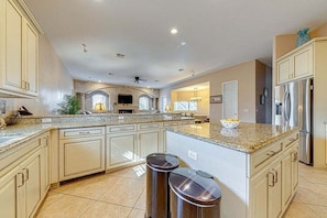 A spacious kitchen with granite countertops, white cabinetry, and stainless steel appliances.