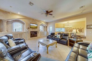 A spacious living room with leather sofas, a fireplace, a ceiling fan, and a large window. - 467- Luxurious, Huge over 6500 sq.ft. private home (Kissimmee)