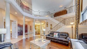 A spacious living area with a high ceiling, a staircase, and a dining area.