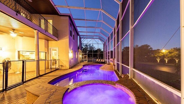 A swimming pool with a glass enclosure, a covered patio area, and a view of the surrounding landscape.