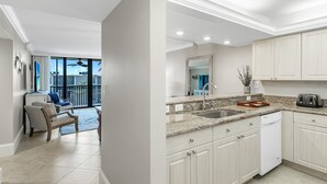 Una cocina moderna con encimeras de granito, lavavajillas y un comedor con una silla y una mesa.