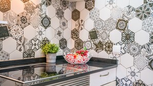 Een keuken met een zwart aanrecht, een wit kastje en een backsplash met een honingraatpatroon.