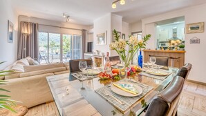 Een moderne woonkamer met een glazen eettafel, een leren bank en uitzicht op de omgeving.