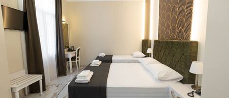 A hotel room with two beds, a desk, a chair, and a TV.
