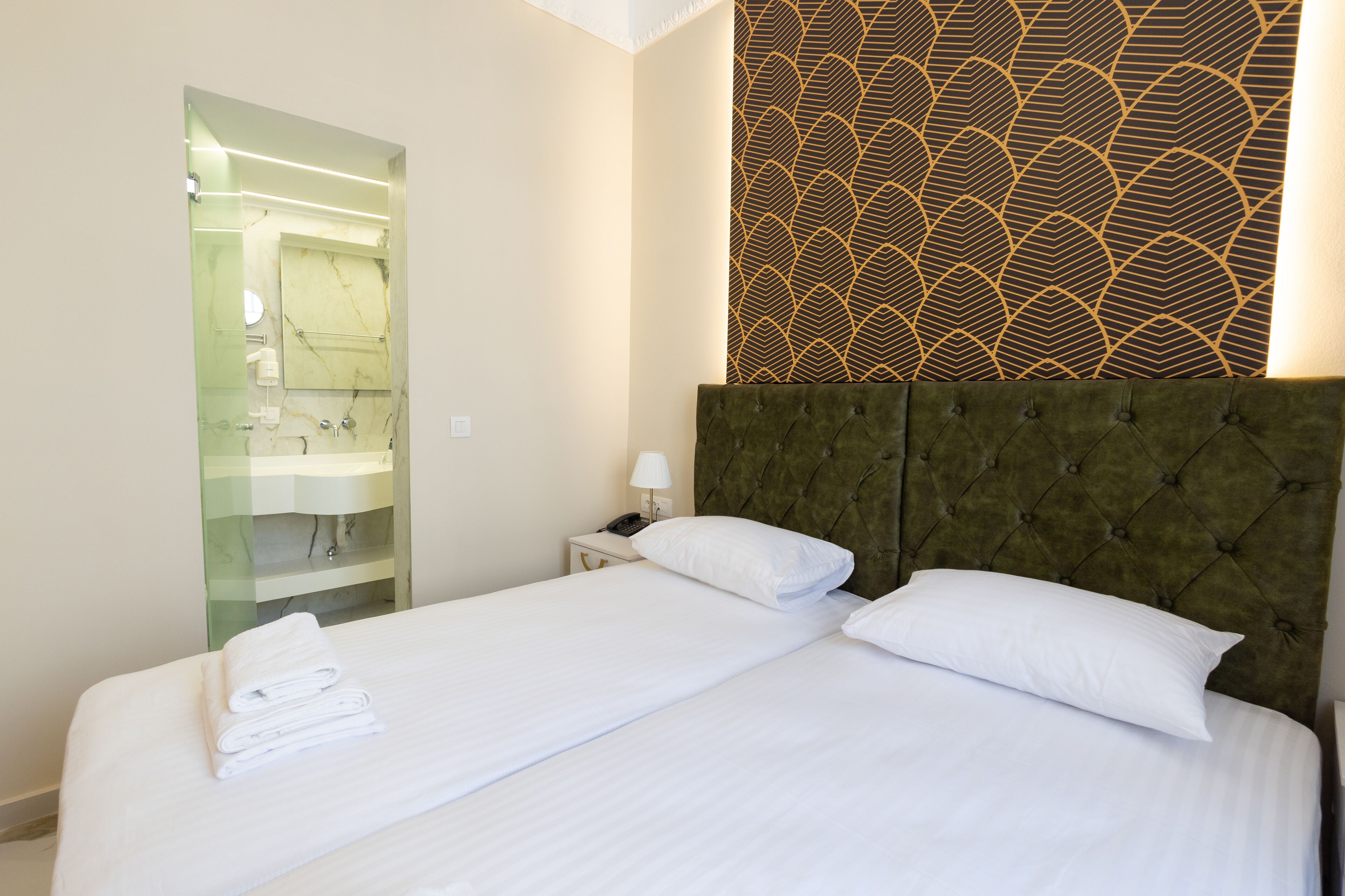 Een hotelkamer met een bed, nachtkastje, spiegel en een kamer met een patroon.