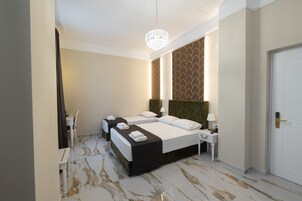 Una camera d'albergo con due letti, un lampadario, un comodino e una porta.