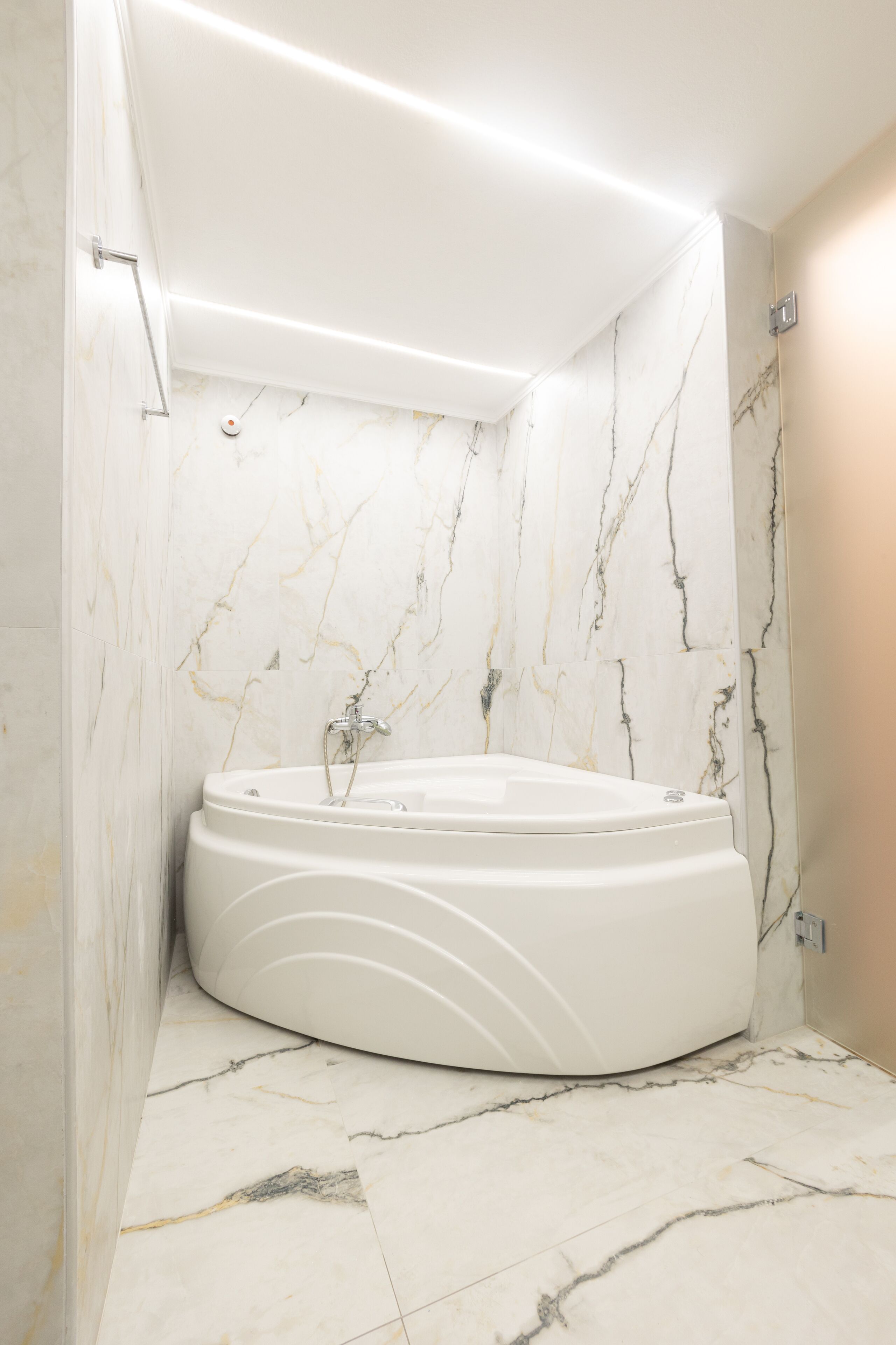 Un baño moderno con una bañera independiente, paredes de mármol y suelo de baldosas.