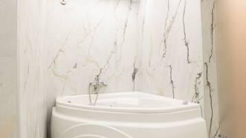 Un baño moderno con una bañera independiente, paredes de mármol y suelo de baldosas.