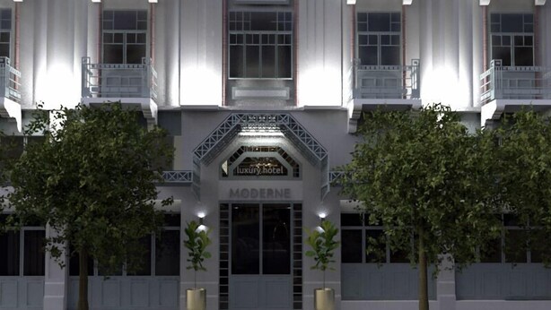 Un hotel moderno con una entrada imponente, dos árboles grandes y un cartel que dice "MODERNE luxury hotel".