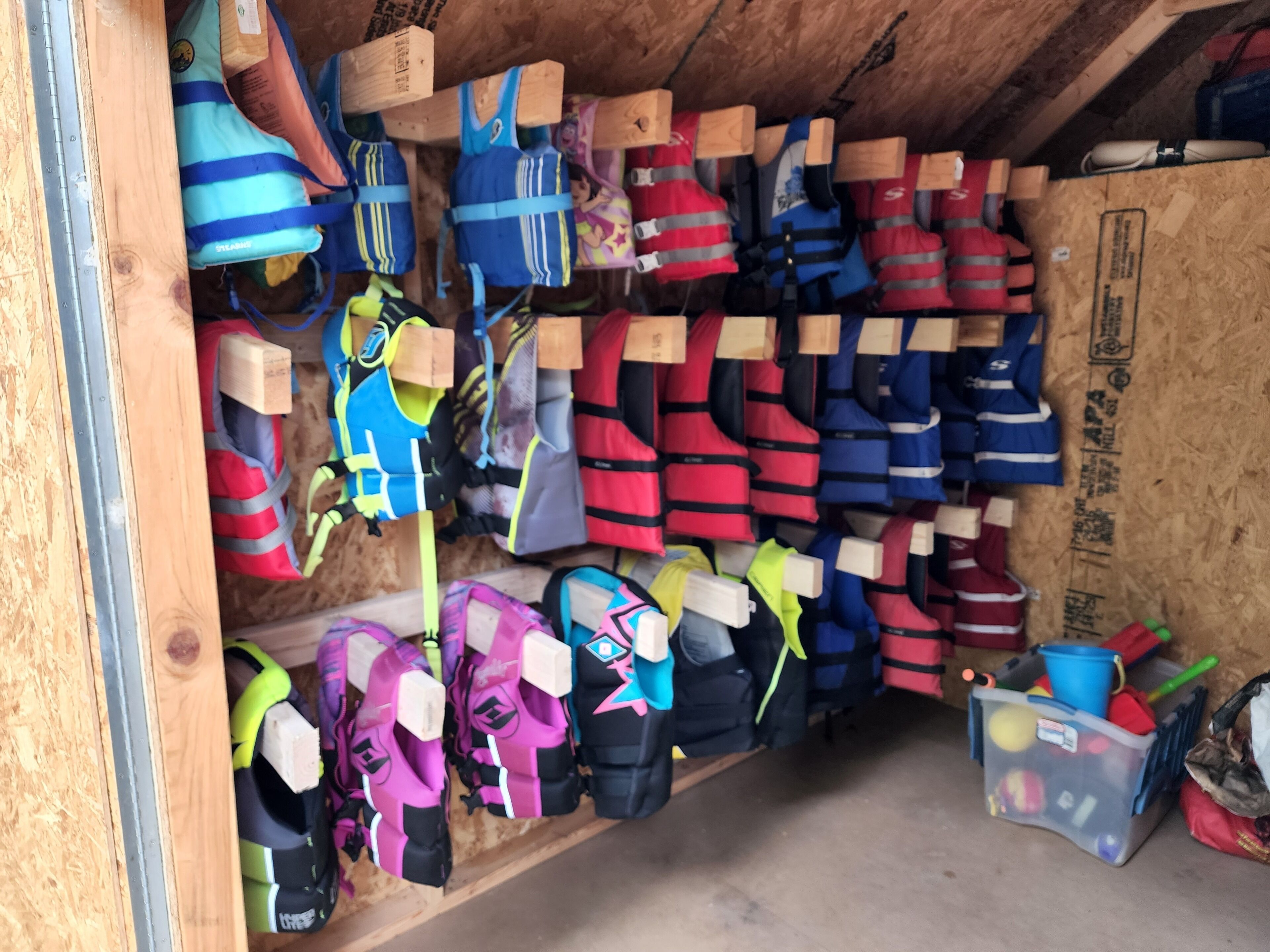 A storage area with various life jackets and safety equipment organized on shelves.