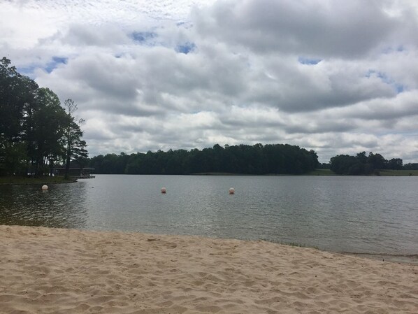 Una playa con orilla arenosa y un lago tranquilo.