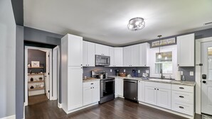 A modern kitchen with white cabinets, a stainless steel microwave, an oven, and a dishwasher.