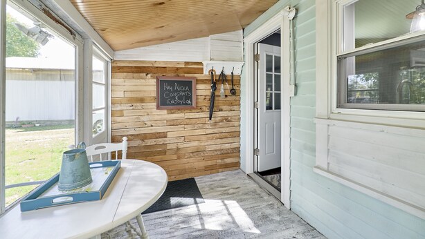 A cozy room with a wooden wall, a chalkboard with a message, a table with a tray, and a door leading outside.