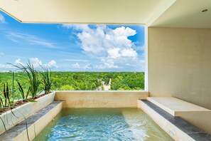 A modern indoor pool with a view of a lush green landscape and a clear blue sky. - Solemn Peaceful Condos by The Spot Rentals (Tulum)