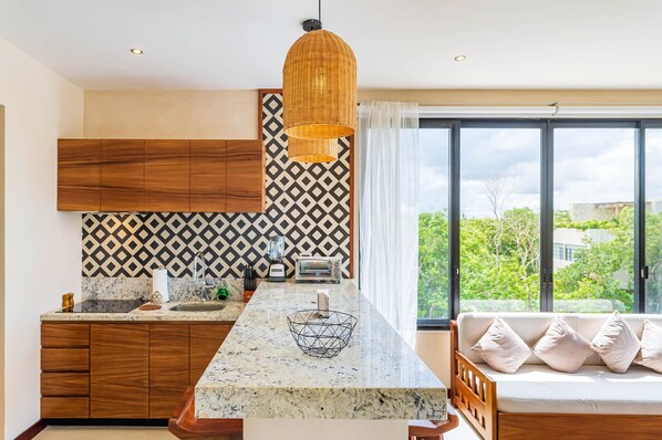 Una cocina moderna con una isla central, armarios de madera, un salpicadero con diseño y un amplio ventanal con vistas a zonas verdes.