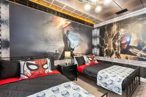A bedroom with two beds, each with themed bedding, a large mural on the wall, and a modern ceiling design.