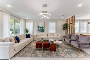 A modern living room with a sectional sofa, a coffee table, and a dining area with chairs.
