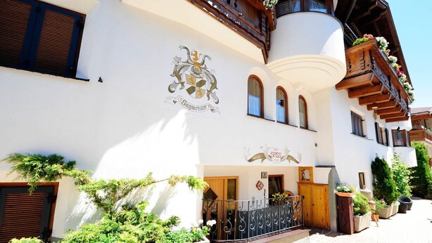 Un bâtiment de style alpin traditionnel, avec une façade blanche, des balcons en bois et une enseigne indiquant qu’il s’agit d’un établissement familial depuis 1997.