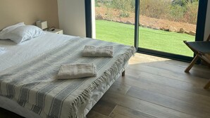 A bedroom with a large bed, a nightstand, and a view of the ocean through a sliding glass door. - Exceptional sea view villa with pool (Conca)