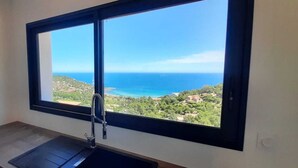 A bathroom with a large window offering a view of the sea and a hillside. - Exceptional sea view villa with pool (Conca)